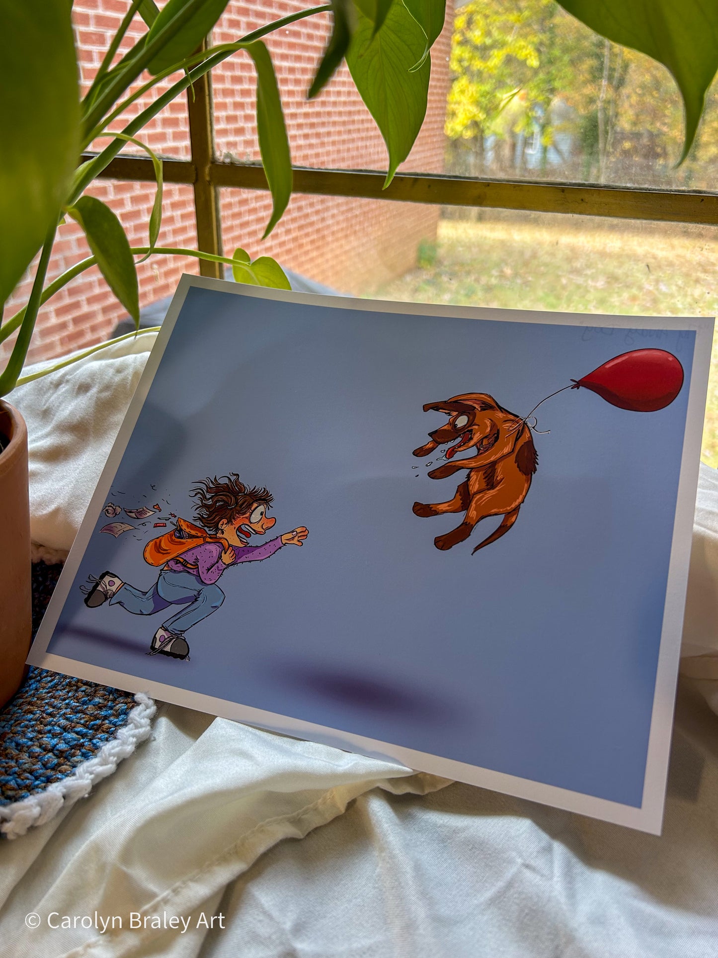 A girl chasing a dog floating into the sky tied to a red balloon on a blue background.